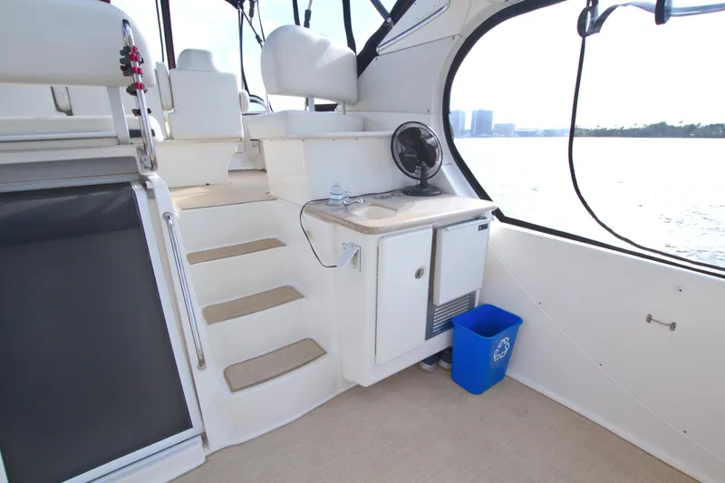 Slide: The Image of 2006 Silverton 39 Motor Yacht interior with stairs, kitchenette, and waterfront view. - 16