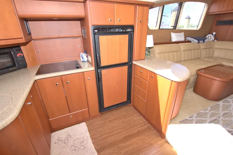 Slide: The Image of 2006 Silverton 39 Motor Yacht interior with kitchen and seating area, featuring wood cabinetry and flooring. - 44
