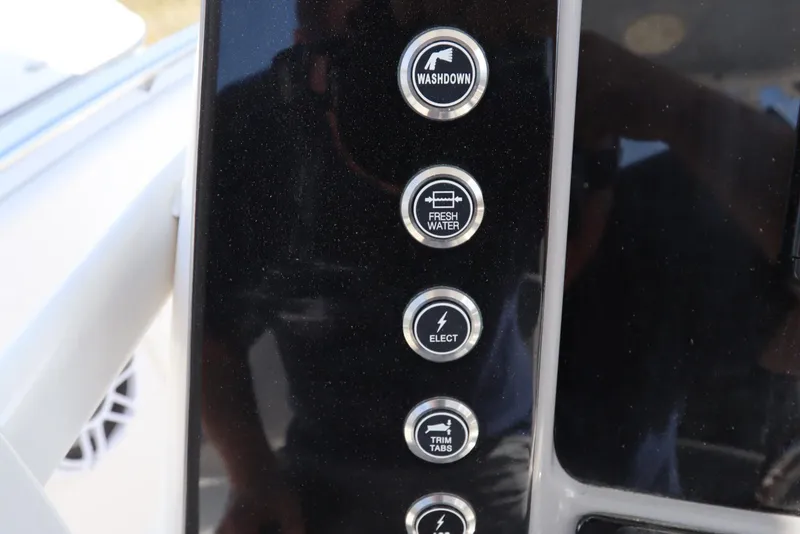Slide: The Image of Control panel of 2021 Robalo R242 Explorer boat with washdown, fresh water, and trim tab buttons. - 19