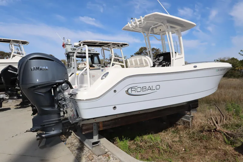 Slide: The Image of 2021 Robalo R242 Explorer boat with Yamaha engine, parked on a stand outdoors. - 2
