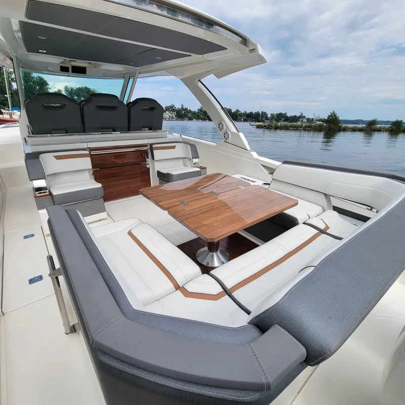 Slide: The Image of 2021 Tiara Yachts 38 LS interior with luxurious seating and wooden table on a serene lake. - 12