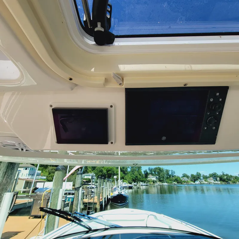 Slide: The Image of 2021 Tiara Yachts 38 LS dashboard with navigation screens, docked by a serene waterfront. - 19