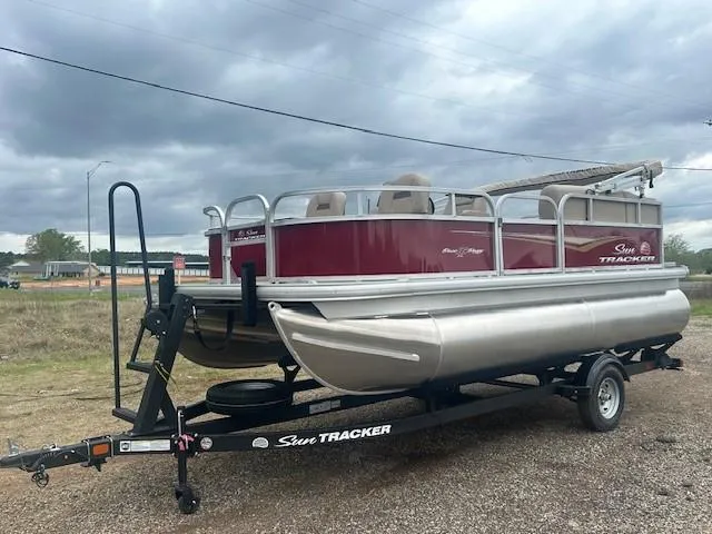 Slide: The Image of 2025 Sun Tracker Bass Buggy 16 XL Select pontoon boat on trailer, under cloudy sky. - 10