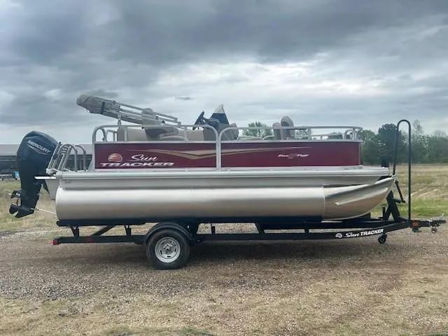 Slide: The Image of 2025 Sun Tracker Bass Buggy 16 XL Select pontoon boat on trailer, overcast sky. - 4