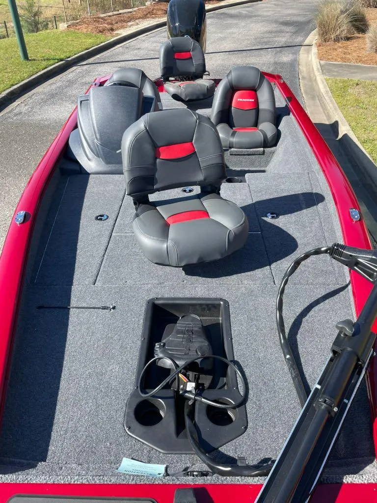 Slide: The Image of 2025 Tracker Pro Team 175 boat with red and gray seating, docked on a sunny day. - 4