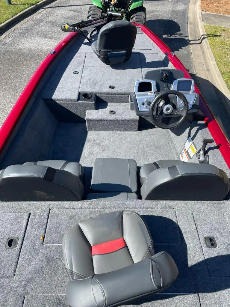Slide: The Image of 2025 Tracker Pro Team 175 boat interior with steering console and seating, featuring red and gray design. - 5