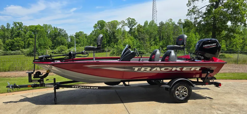 Slide: The Image of 2025 Tracker Pro Team 175 boat on trailer, red color, parked outdoors. - 2