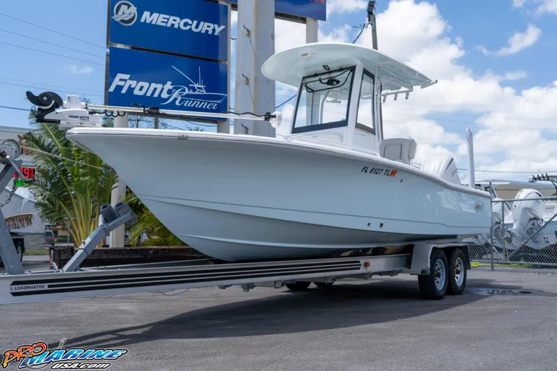 Slide: The Image of 2022 Sea Hunt BX 25 FS boat on trailer at dealership, clear sky background. - 0