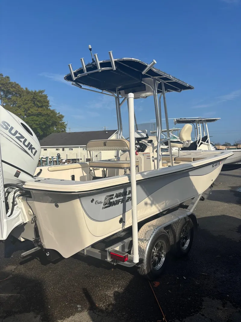 Slide: The Image of 2023 Carolina Skiff 21 LS boat with Suzuki engine on trailer, parked outdoors. - 0
