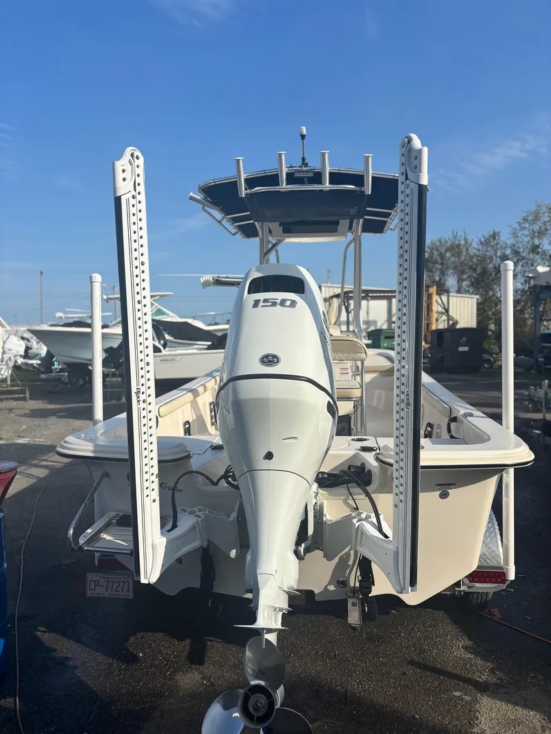 Slide: The Image of 2023 Carolina Skiff 21 LS boat with powerful outboard motor, docked under clear blue sky. - 1