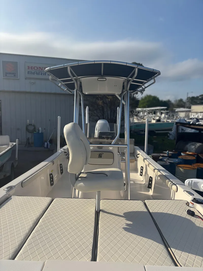 Slide: The Image of 2023 Carolina Skiff 21 LS boat with T-top and cushioned seating, docked outdoors. - 3