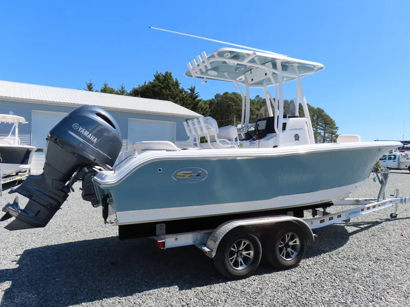 Slide: The Image of 2021 Sea Hunt Ultra 219 boat on trailer with Yamaha outboard motor, parked outdoors. - 2