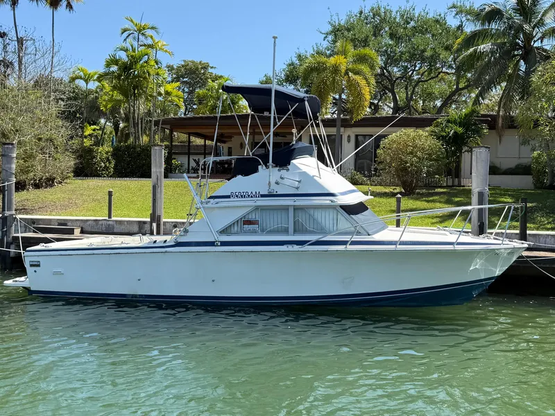 Slide: The Image of 1979 Bertram 28 Flybridge Cruiser docked by lush greenery and clear water. - 1