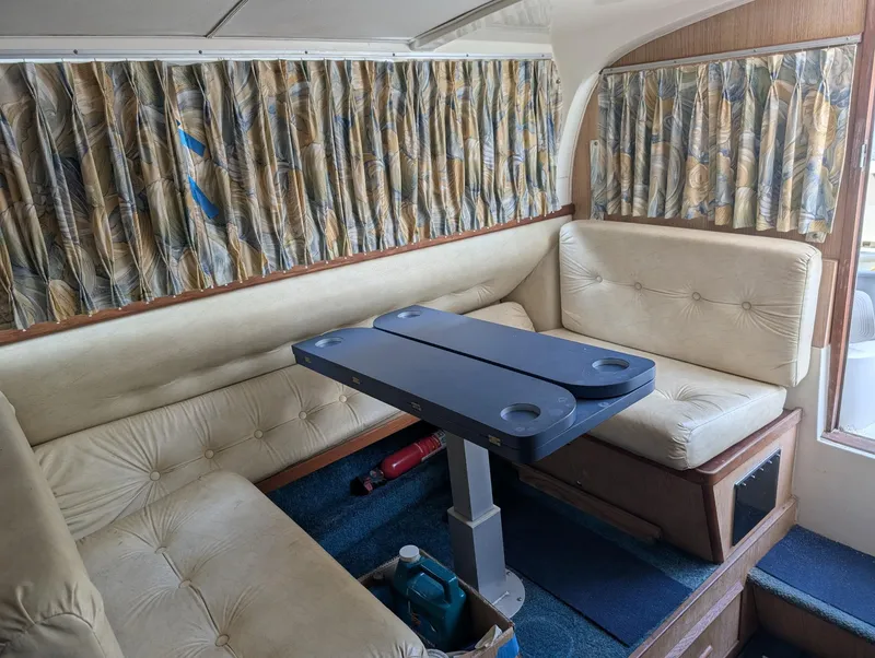 Slide: The Image of Interior of 1979 Bertram 28 Flybridge Cruiser with beige seating and patterned curtains. - 4