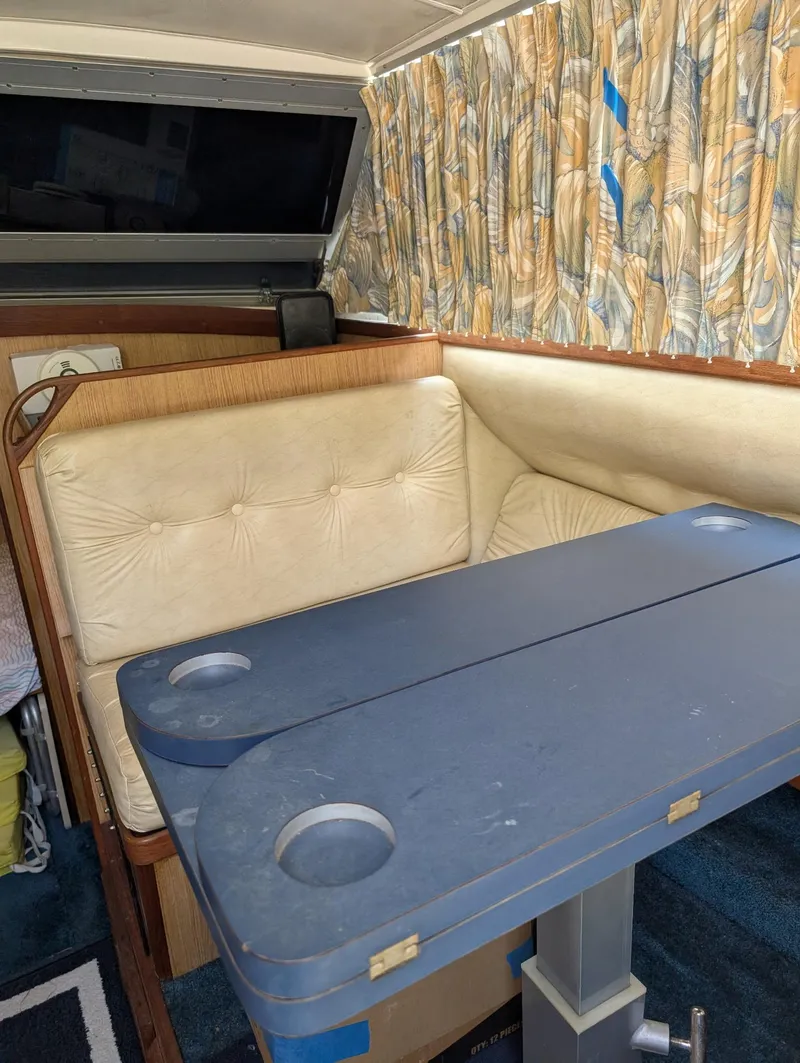 Slide: The Image of Interior of a 1979 Bertram 28 Flybridge Cruiser with cushioned seating and a blue table. - 5
