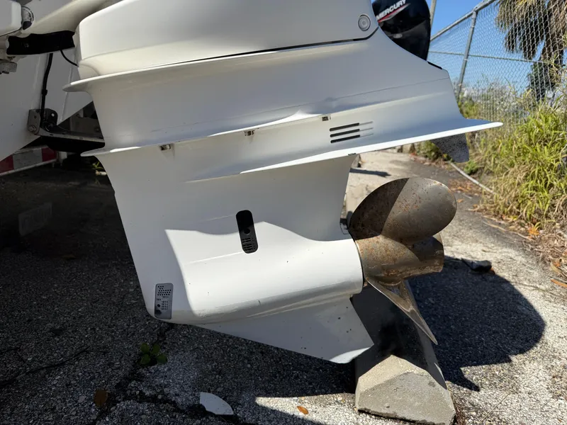 Slide: The Image of Propeller of 2018 Everglades 230 Center Console boat on pavement, near fence and vegetation. - 8