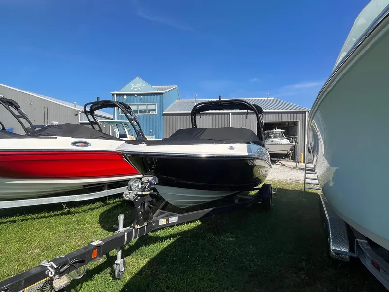Slide: The Image of 2025 Bayliner VR5 Bowrider OB on trailer, parked outdoors under clear blue sky. - 12