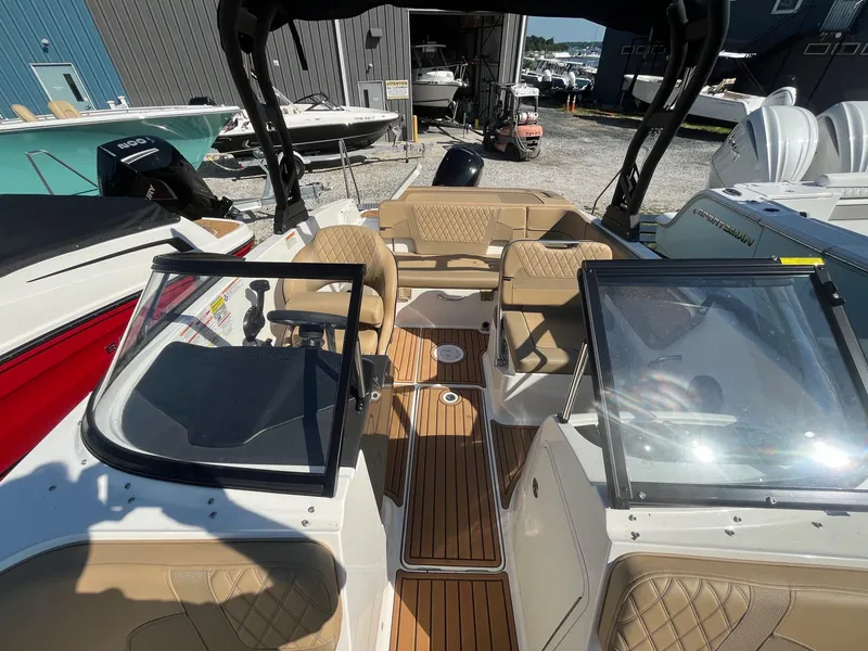 Slide: The Image of 2025 Bayliner VR5 Bowrider OB with tan seating and wood-style flooring in a marina setting. - 23