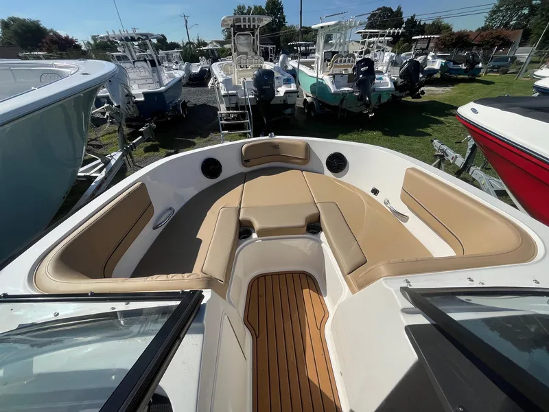 Slide: The Image of 2025 Bayliner VR5 Bowrider OB with tan seating and wood-style flooring, docked among other boats. - 24