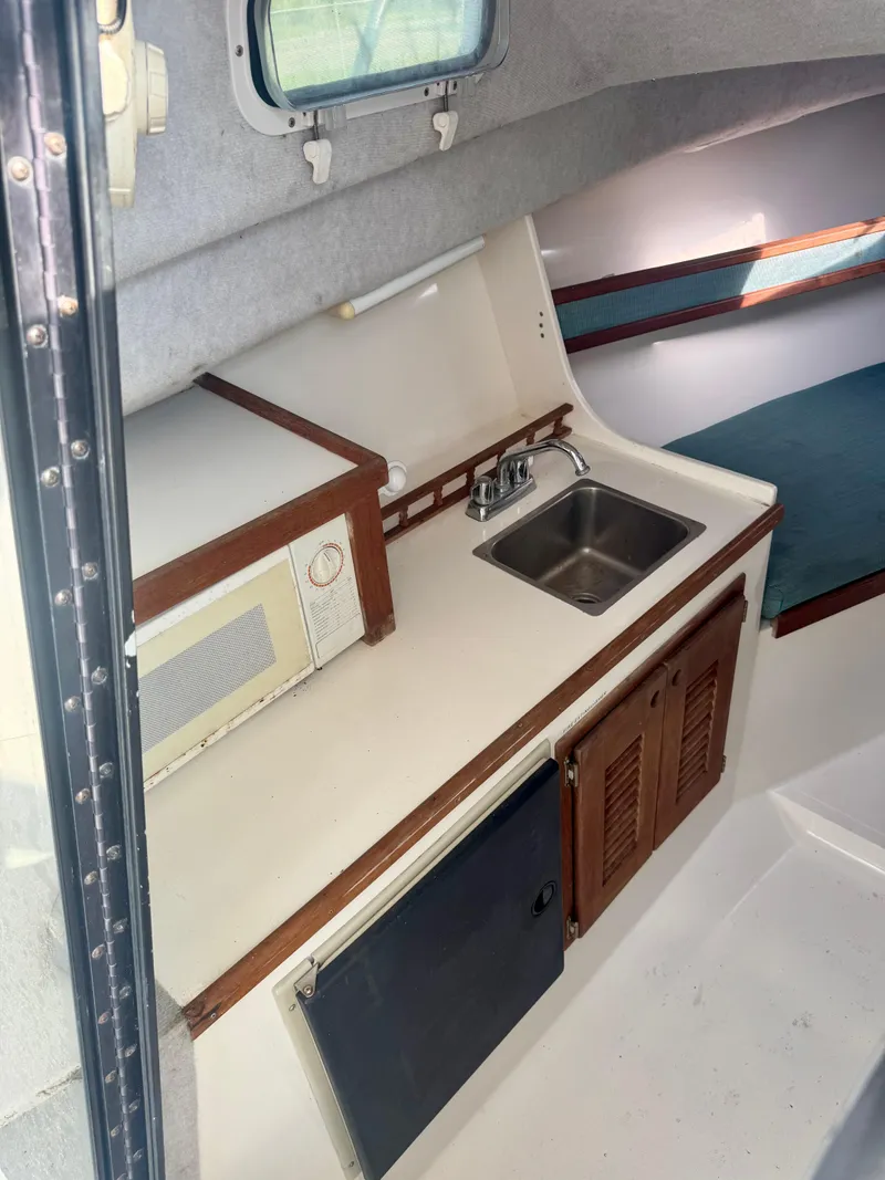 Slide: The Image of 1998 Regulator 26 Express boat interior with kitchenette, sink, and storage cabinets. - 10