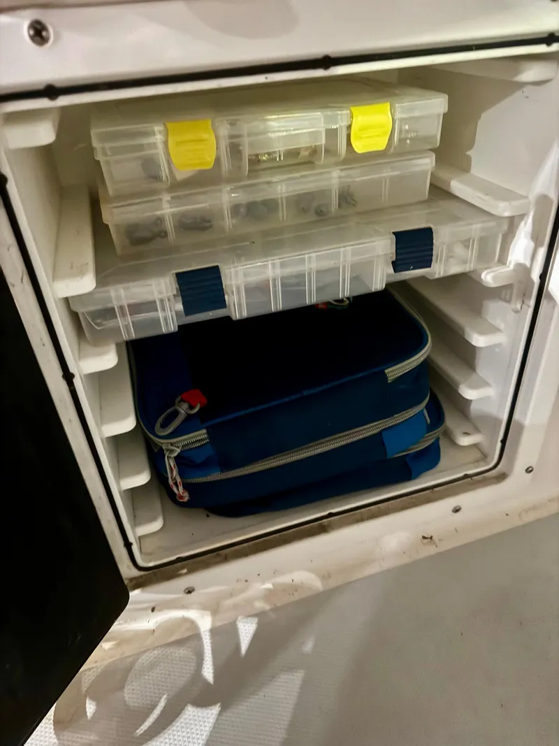 Slide: The Image of Storage compartment on a 1998 Regulator 26 Express boat with organized tackle boxes. - 19