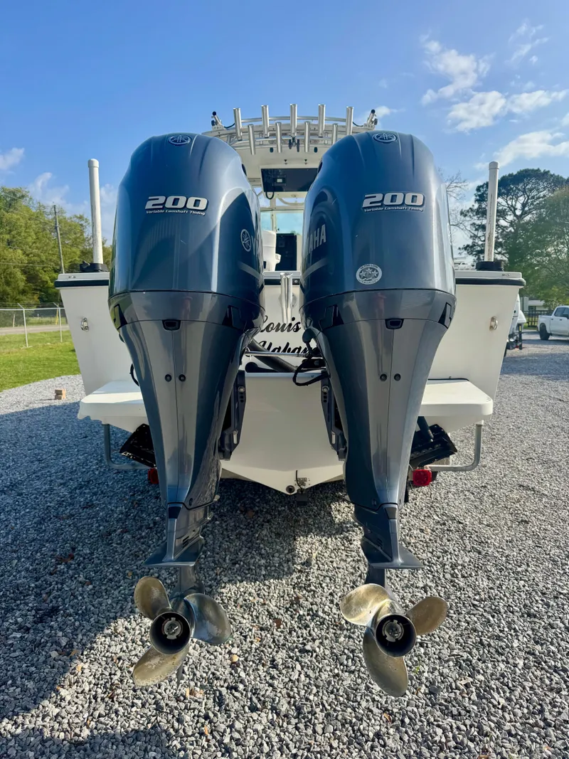 Slide: The Image of 1998 Regulator 26 Express boat with twin 200 horsepower engines, parked on gravel. - 5