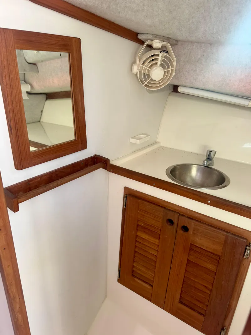 Slide: The Image of 1998 Regulator 26 Express boat cabin with sink, mirror, and wooden cabinets. - 8
