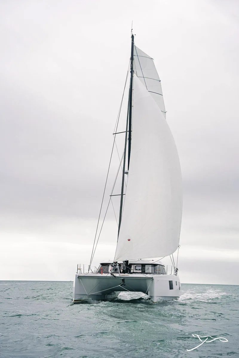 Slide: The Image of 2025 Nautitech 40 Open catamaran sailing on open sea under cloudy skies. - 2