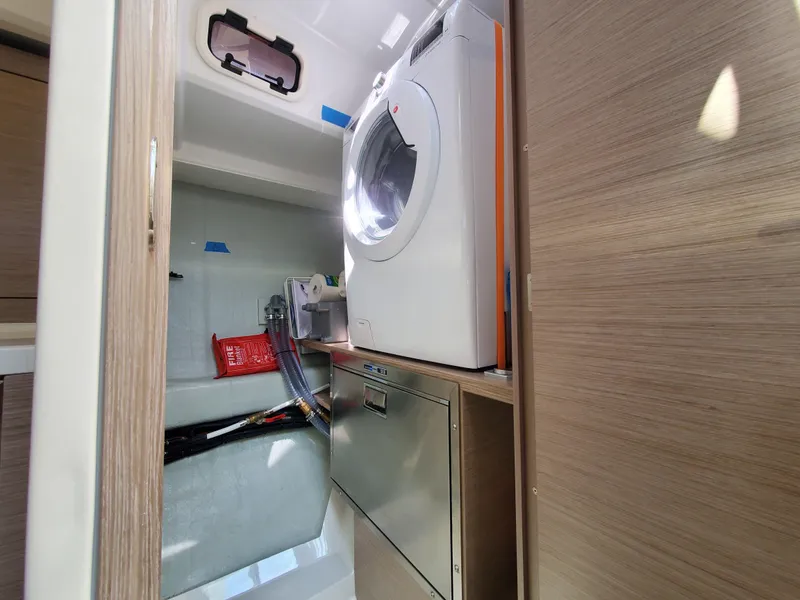Slide: The Image of Laundry area inside 2023 Hanse 460 yacht, featuring a washing machine and storage space. - 33