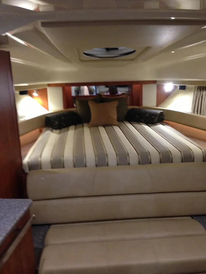 Slide: The Image of 2013 Monterey 340 SY cabin interior with striped bedding and cozy lighting. - 16