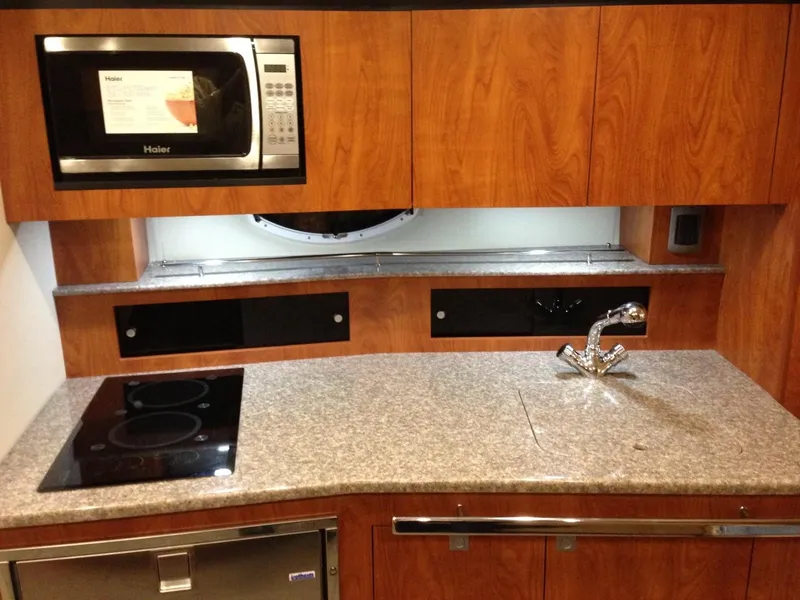Slide: The Image of 2013 Monterey 340 SY yacht kitchen with microwave, stovetop, sink, and wooden cabinetry. - 18