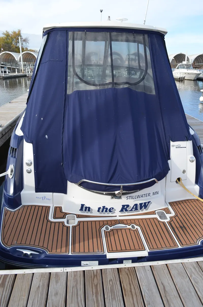 Slide: The Image of 2013 Monterey 340 SY boat docked, featuring a blue cover and wooden deck. - 5