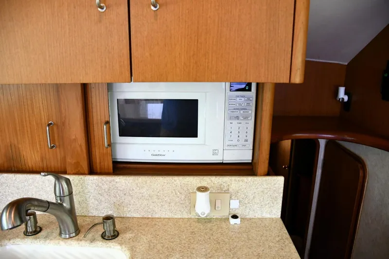 Slide: The Image of 2001 Ocean Yachts 43 Super Sport kitchen with microwave, sink, and wooden cabinetry. - 15
