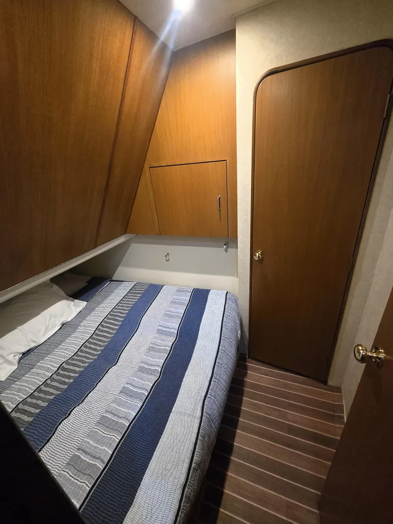 Slide: The Image of 2001 Ocean Yachts 43 Super Sport cabin with bed, wooden walls, and striped bedding. - 23