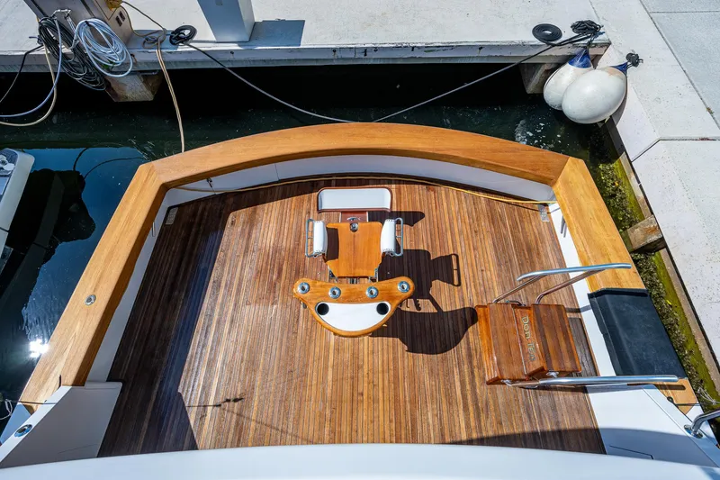 Slide: The Image of 2001 American Custom Enclosed Flybridge boat deck with wooden flooring and fishing chair. - 14