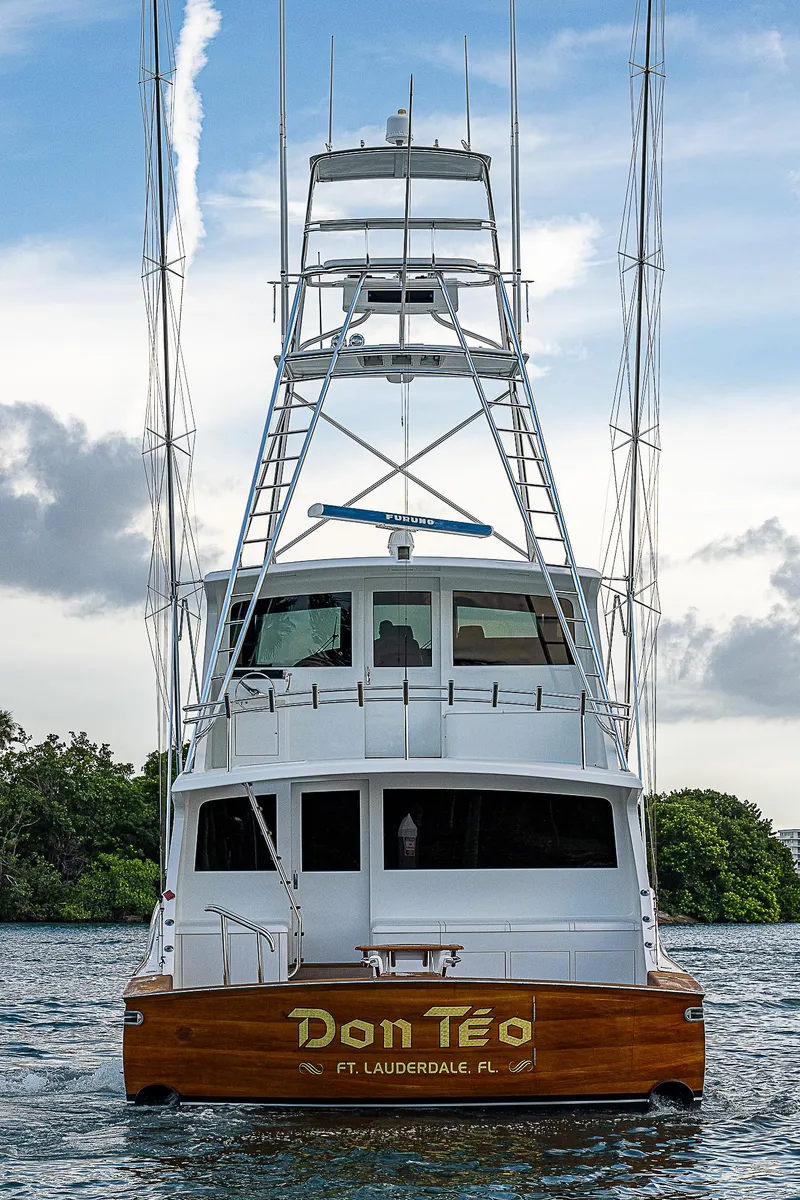 Slide: The Image of 2001 American Custom Enclosed Flybridge yacht on water, rear view, with tower and lush background. - 6
