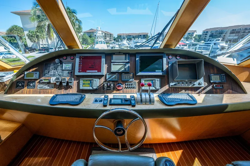 Slide: The Image of 2001 American Custom Enclosed Flybridge helm with advanced navigation equipment and marina view. - 7