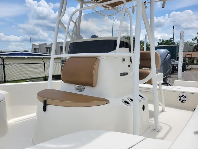 Slide: The Image of 2016 Ranger 220 Bahia boat with tan seating and white console under a blue sky. - 12