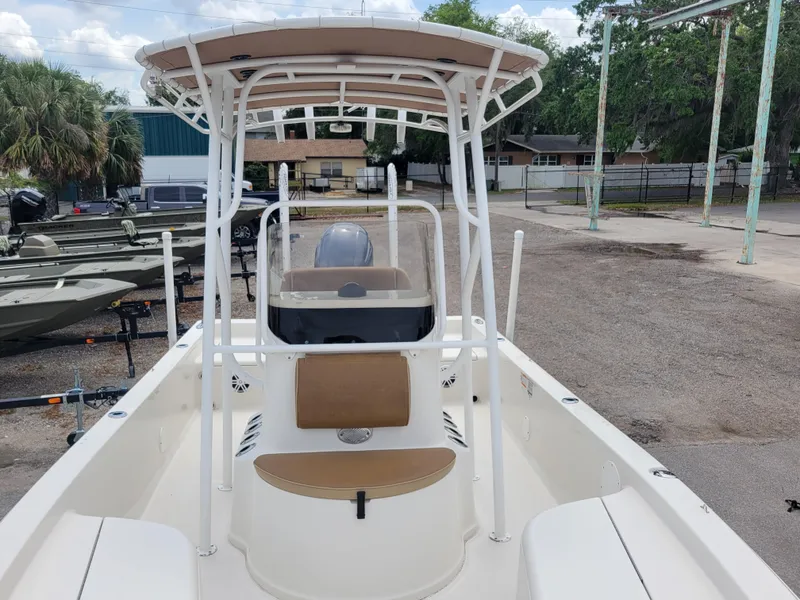 Slide: The Image of 2016 Ranger 220 Bahia boat with T-top, center console, and seating, parked outdoors. - 14