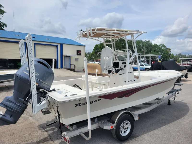 Slide: The Image of 2016 Ranger 220 Bahia boat on trailer with Yamaha outboard motor, parked near blue-roofed building. - 4