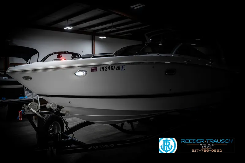 Slide: The Image of 2021 Four Winns H260 boat on trailer in dimly lit indoor setting. - 4