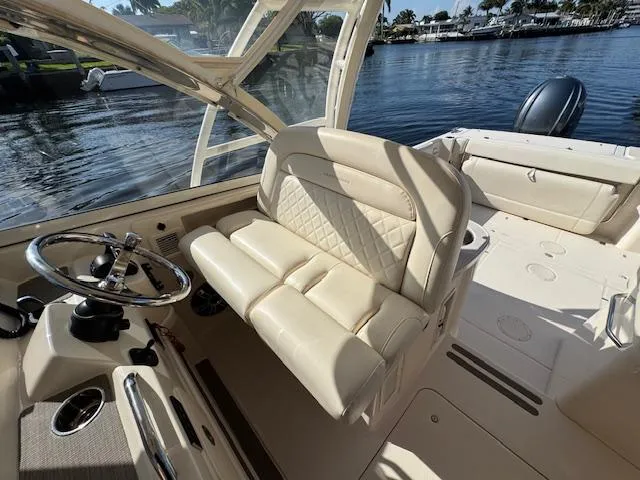 Slide: The Image of 2021 Grady-White Freedom 335 boat interior with beige seating and steering wheel, docked by water. - 40