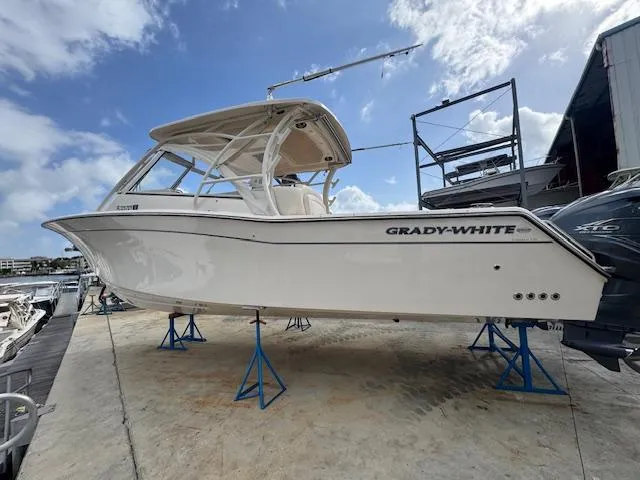 Slide: The Image of 2021 Grady-White Freedom 335 boat on stands, dockside, under a partly cloudy sky. - 7
