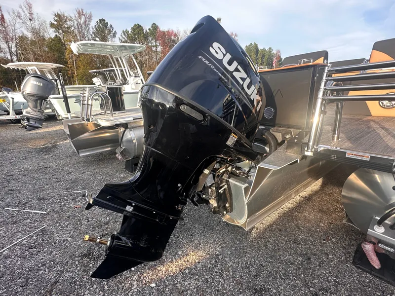 Slide: The Image of Outboard motor on 2025 Avalon LSZ Quad Lounger Shift pontoon boat, gravel lot background. - 2