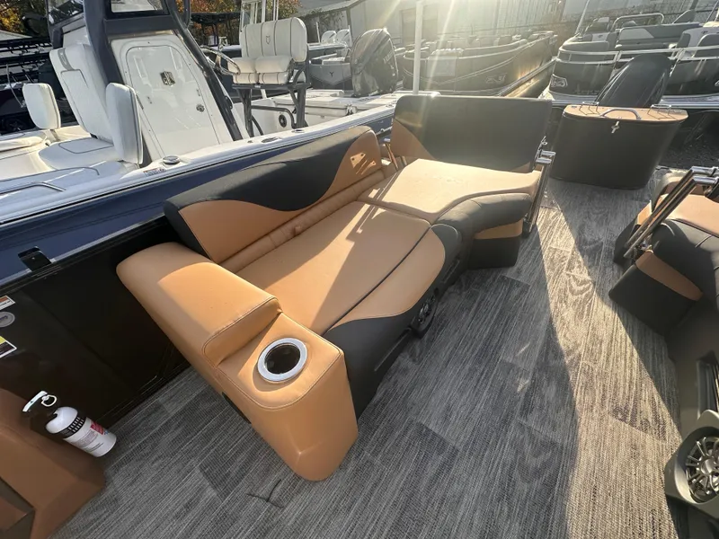 Slide: The Image of 2025 Avalon LSZ Quad Lounger Shift boat interior with tan and black seating, cup holder, and sunlit deck. - 3