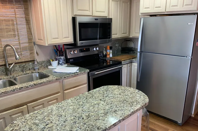 Slide: The Image of Modern kitchen with granite countertops, stainless steel appliances, and wooden cabinets in a 1997 Lakeview model. - 17