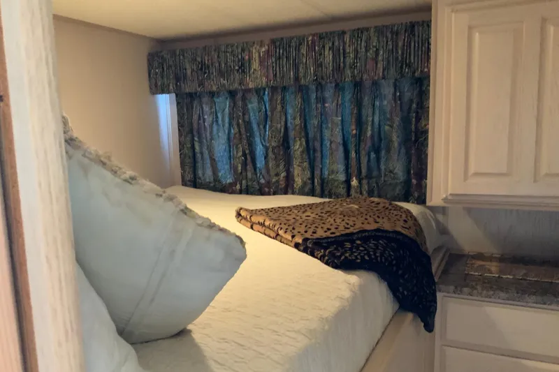 Slide: The Image of Cozy bedroom in 1997 Lakeview 16 x 65 houseboat with patterned curtains and plush bedding. - 23