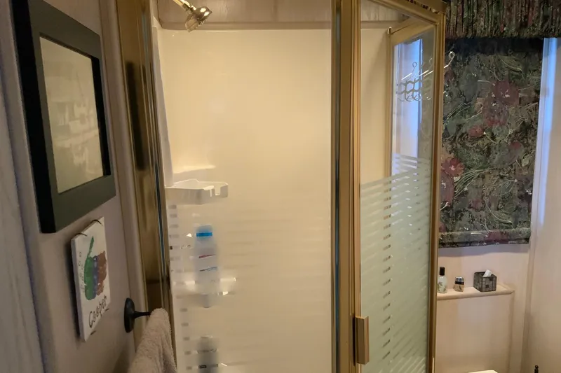 Slide: The Image of Shower area in a 1997 Lakeview 16 x 65 houseboat bathroom with glass door and toiletries. - 30