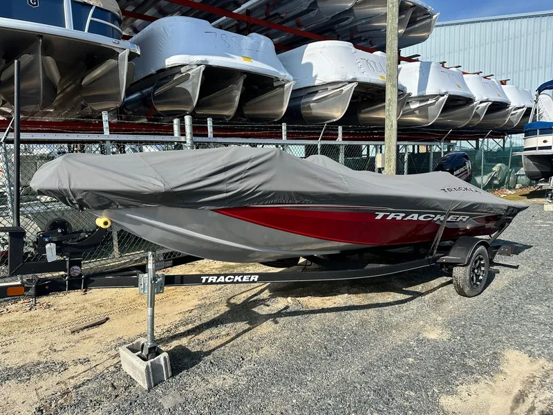 Slide: The Image of 2019 Tracker TXW175 Tournament Edition boat covered, stored outdoors, surrounded by other boats. - 2