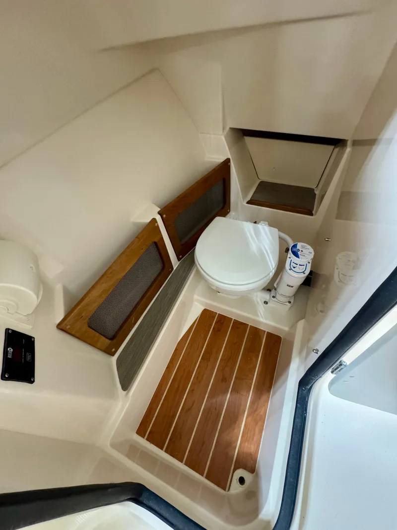 Slide: The Image of 2025 Grady-White Freedom 235 boat interior with wooden flooring and compact toilet. - 12
